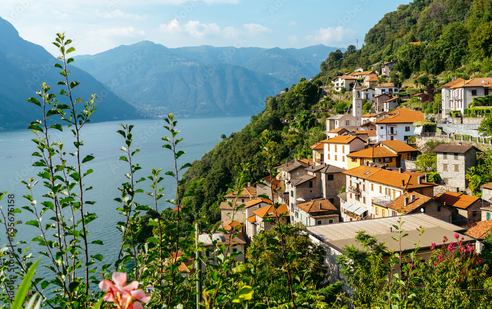 Italy, Lake Lugano. View of the lake, mountains and old houses above the lake.