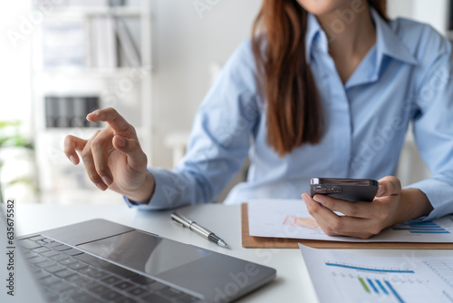 Happy young asian female accountant Positive concept using smartphone at her desk to relax with mobile application and use to chat business contact online marketing Excellent profit.