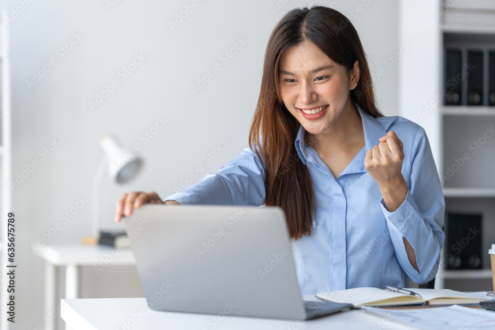 Happy young asian businesswoman sitting on her workplace in the office. Young woman working at laptop in the office Happy young asian businesswoman sitting on her workplace in the office. Young woman working at laptop in the office