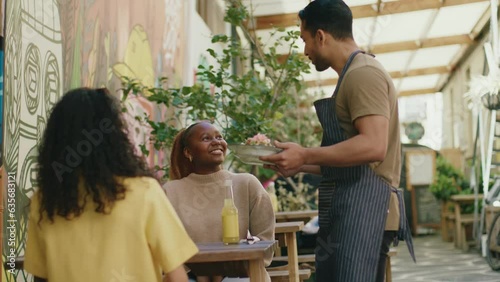 Young multiracial friends in casual clothing getting served healthy food for lunch at vegan cafe 