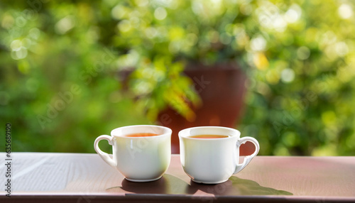 Two cups of tea or coffee on table on garden bright background