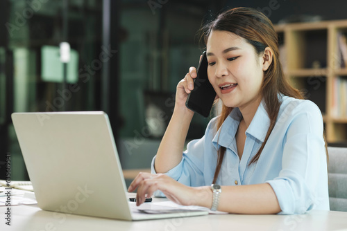 Smiling businesswoman talking on smartphone while waiting client in office © ijeab