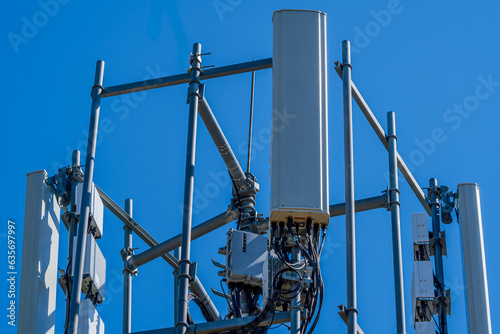 Close-up of tower with 6G, 5G, 4G cellular network antenna on blue sky background. cellular antenna with many power cables, coaxial cables, optical fiber.