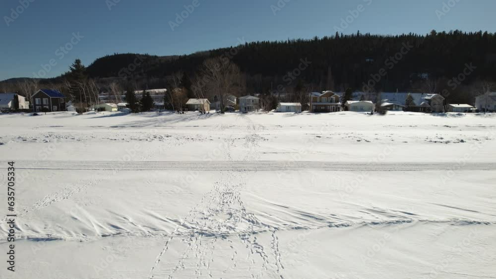 Flying drone above footsteps in the snow on a frozen lake during winter in canada Flying drone above footsteps in the snow on a frozen lake during winter in canada