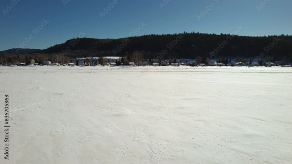 Flying drone above houses and a frozen lake during winter in canada Flying drone above houses and a frozen lake during winter in canada