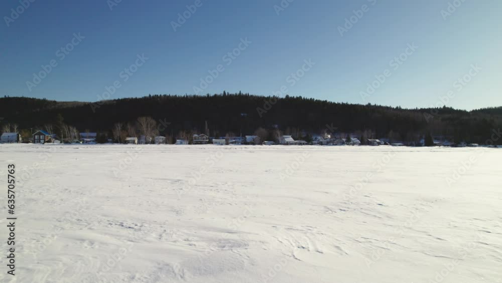 Flying drone above houses and a frozen lake during winter in canada Flying drone above houses and a frozen lake during winter in canada
