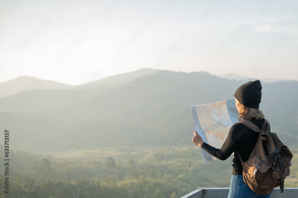 Adventurous girl navigating in with a topographic map in beautiful mountains of thailand. woman wearing hat stand alone and enjoying freedom and calm inspired travelling on background view mockup.