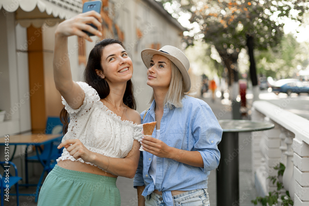 Summer lifestyle concept. Happy young woman eating ice cream cones on city street. Female friends enjoying ice cream outside Summer lifestyle concept. Happy young woman eating ice cream cones on city street. Female friends enjoying ice cream outside