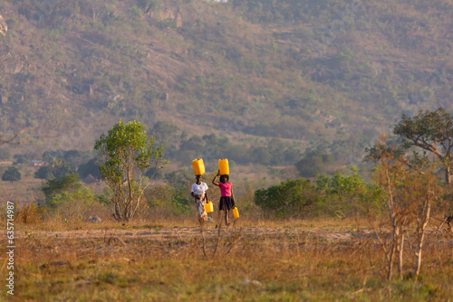 Two girls carrying gallons of Water on their heads in a water-scarce region