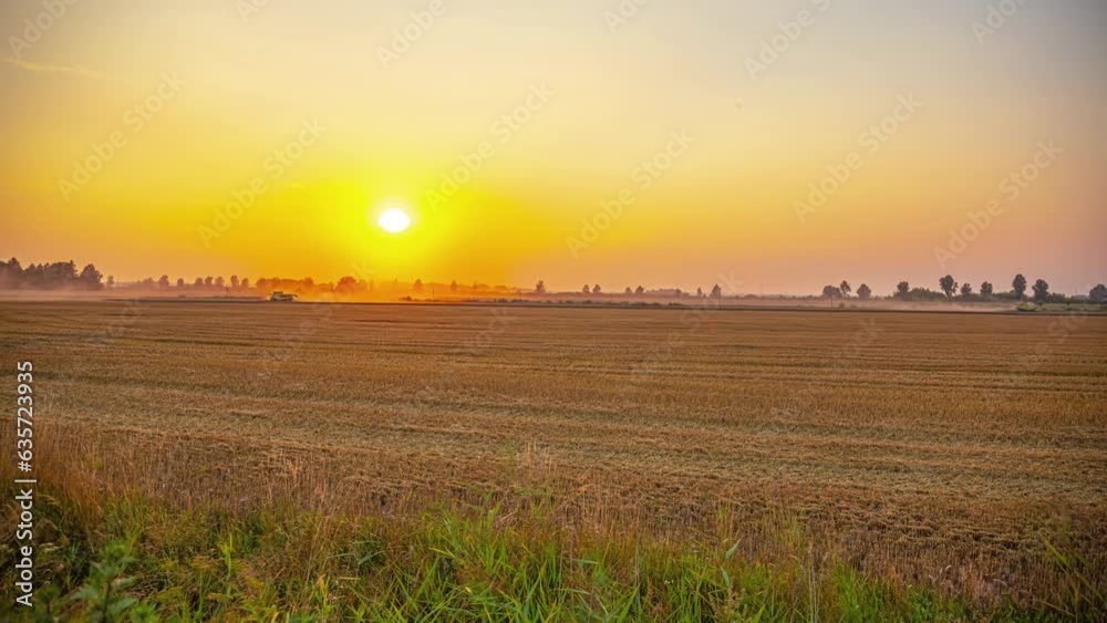 Cinematic timelapse of tractors working on a field while the sun is setting in the background on a beautiful and cloudless day
