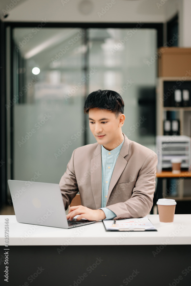 Young Asian business man working at office with laptop, tablet and taking notes on the paper. Young Asian business man working at office with laptop, tablet and taking notes on the paper.
