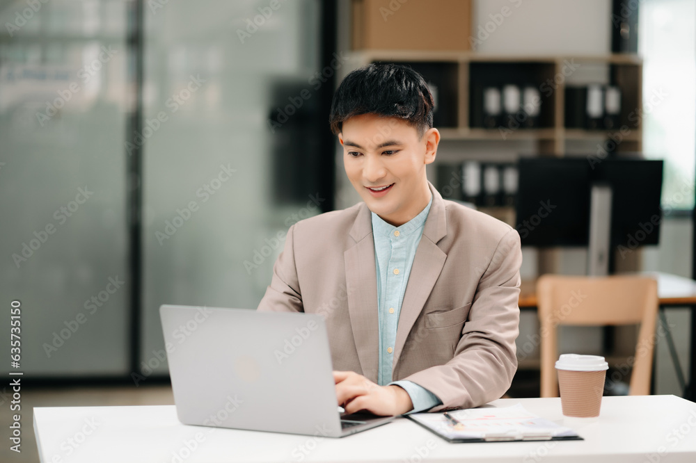 Young Asian business man working at office with laptop, tablet and taking notes on the paper. Young Asian business man working at office with laptop, tablet and taking notes on the paper.