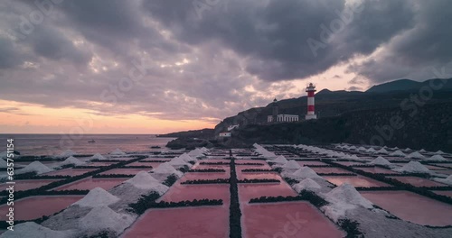 Timelapse of Salinas de Fuencaliente salt pans leading lines and lighthouse during colorful sunset with orange and red clouds photo