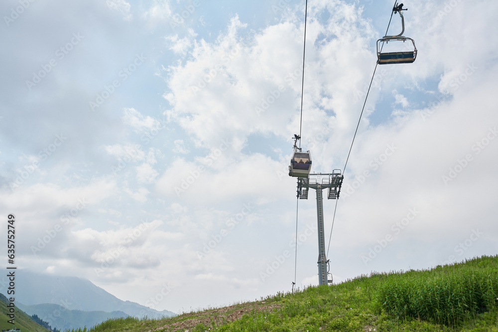 Empty chairlift in ski resort. Shot in summer with green grass and no snow. Cloudy weather.