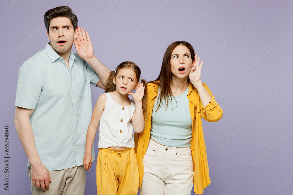 Young happy parents mom dad with child kid daughter girl 6 years old wear blue yellow casual clothes try to hear you overhear listening intently isolated on plain purple background Family day concept Young happy parents mom dad with child kid daughter girl 6 years old wear blue yellow casual clothes try to hear you overhear listening intently isolated on plain purple background Family day concept