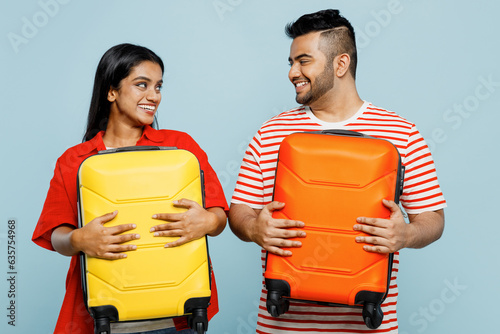 Traveler fun Indian man woman wear red casual clothes hold suitcase bag isolated on plain blue color background. Tourist travel abroad in free spare time rest getaway. Air flight trip journey concept. #635754968