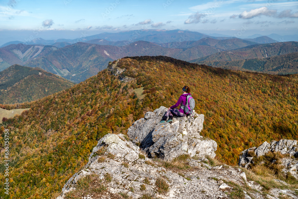 Woman hiker sitting on th rock on top of the hill Klak and looking on beautiful mountain landscape under