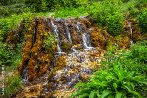 Flowing water through travertine rocks in forest photo