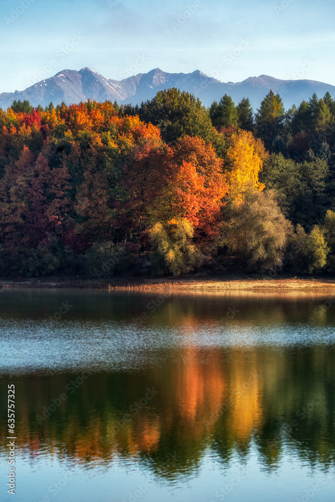Reflection of colorful trees over lake with mountains at background