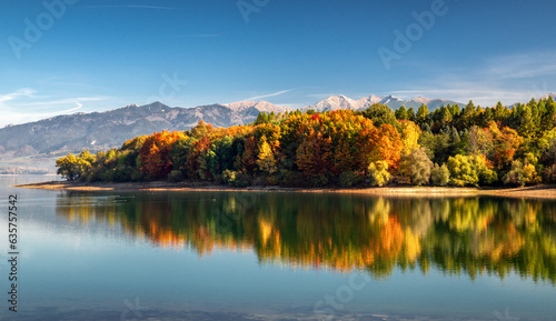 Panoramic autumn landscape. Colorful trees, lake and mountains at background