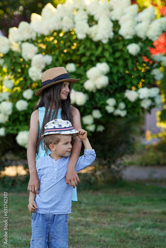 A boy and a girl in retro hats and summer clothes have fun on a blooming background. A fun family vacation.