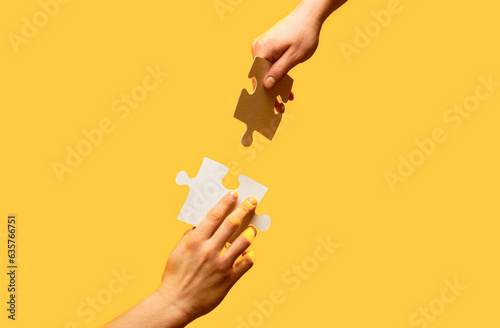 Hand connecting jigsaw puzzle. Man hands connecting couple puzzle piece. Closeup hands of man connecting jigsaw puzzle. Two hands trying to connect couple puzzle with yellow background