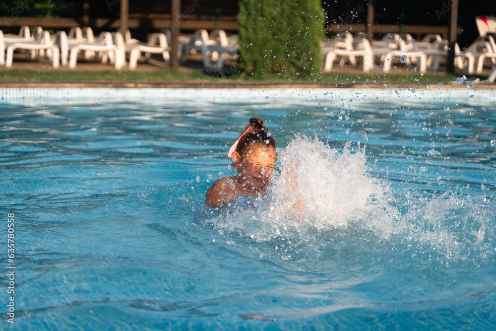 Child girl relaxing at the pool on a sunny hot summer day. Poolside resort concept, heat wave, climate change 