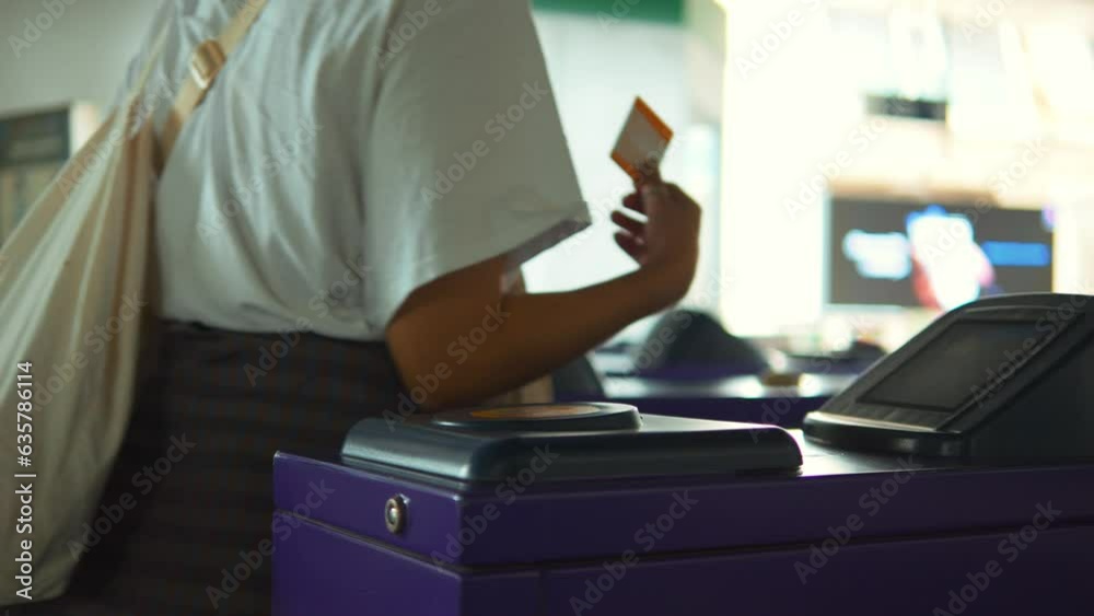 Passenger woman using contactless ticket for passing turnstile subway entrance gate at train station, high quality 4K big city transportation concept. Bangkok, Thailand.
