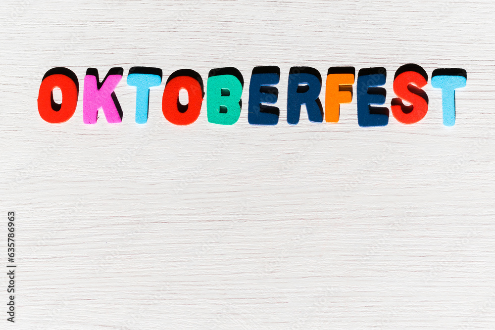 colored letters with the word oktoberfest on a light colored wooden background and space for work

