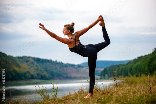 the girl does yoga on the river bank