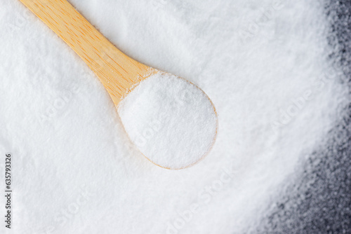 White sugar with a spoon on a wooden board, grape sugar, selective focus.