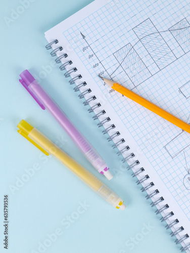 Close-up of a yellow slate pencil  and pencil eraser lying on a checkered notebook, ready to start work