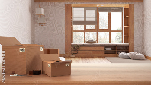 Wooden table, desk or shelf with stack of cardboard boxes over blurred view of meditation room with capet and pillows, modern interior design, moving house concept with copy space © ArchiVIZ