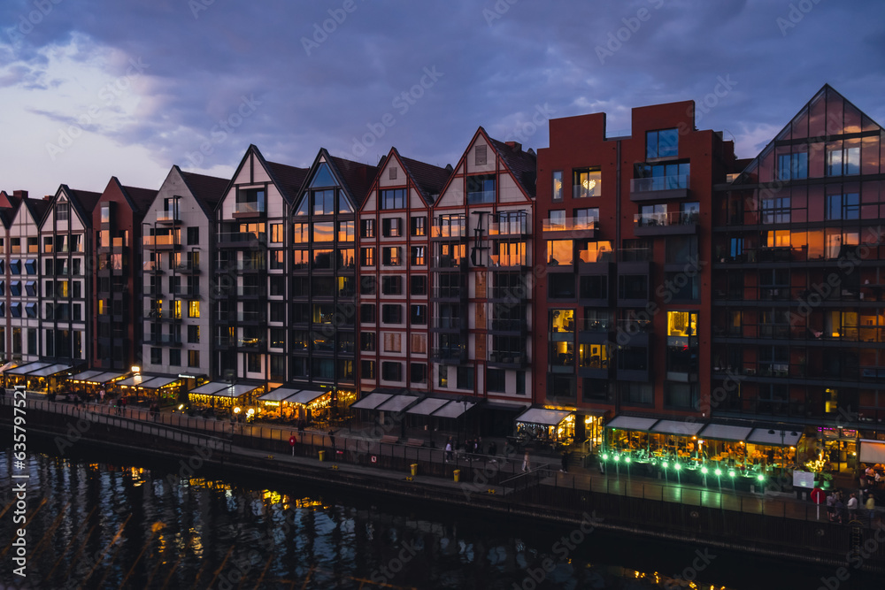 Fototapeta premium Old town in Gdansk at summer dusk Poland. Sunset night view from the window rooftop on new modern architecture buildings Hotels to stay in Gdansk Place to eat over Motlawa river Wyspa Spichrzow Travel