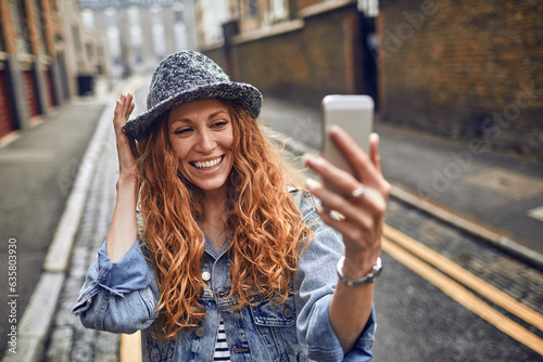 Young redhead woman using a smart phone on a city street photo