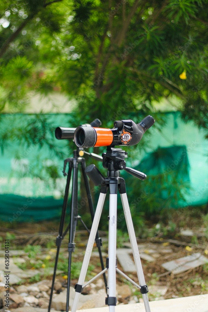 Spotting scope mounted on tripod at an outdoor archery target range, featuring three boards