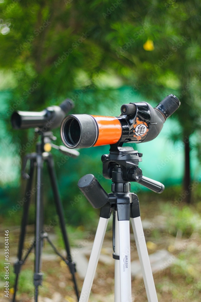 Spotting scope mounted on tripod at an outdoor archery target range, featuring three boards Spotting scope mounted on tripod at an outdoor archery target range, featuring three boards