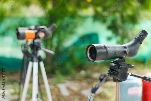 Spotting scope mounted on tripod at an outdoor archery target range, featuring three boards