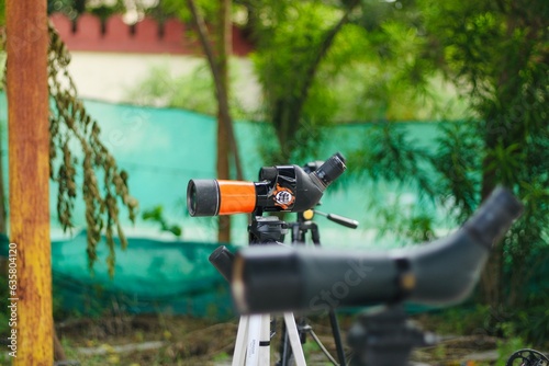 Spotting scope mounted on tripod at an outdoor archery target range, featuring three boards
