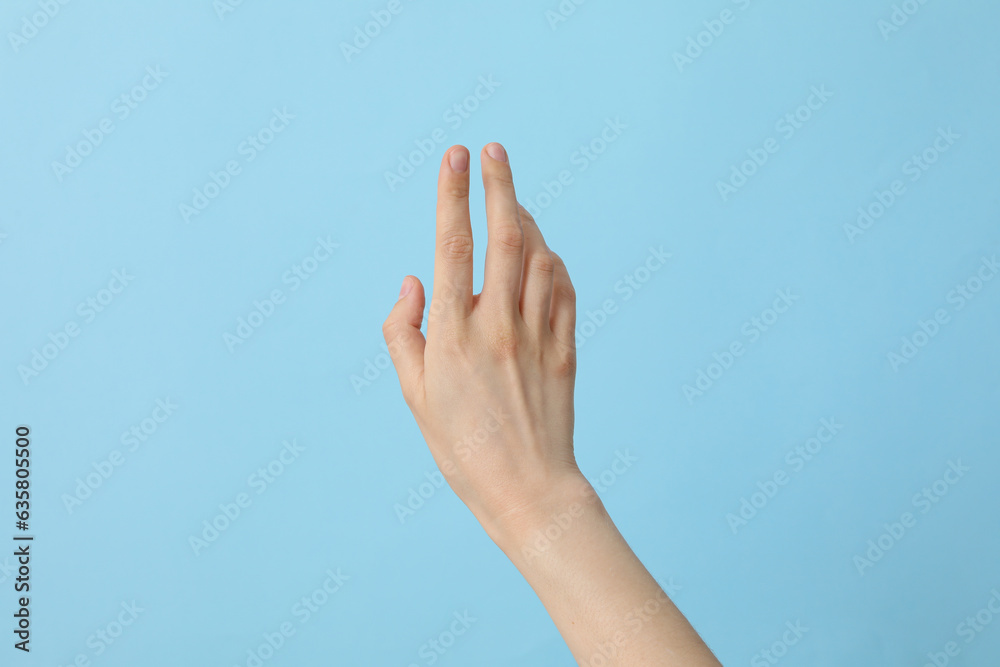 Female well-groomed hand on a light blue background Female well-groomed hand on a light blue background
