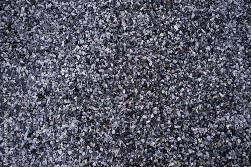 Small pebble stone background, dark wet gravel and gray dry gravel. Black small road
