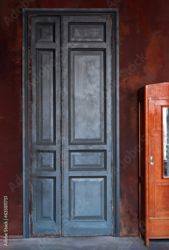 Vintage teal green wooden door on dark red exterior wall. Retro interior concept with copy space.