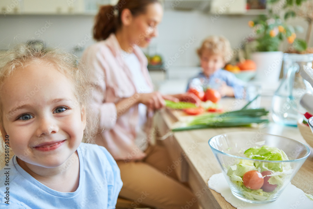 Smiling girl with bowl of vegetable on table at home Smiling girl with bowl of vegetable on table at home