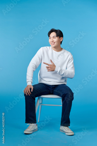 man sitting on a chair look side on blue background