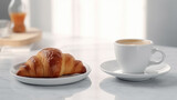 Croissant on a plate, coffee in the background.
