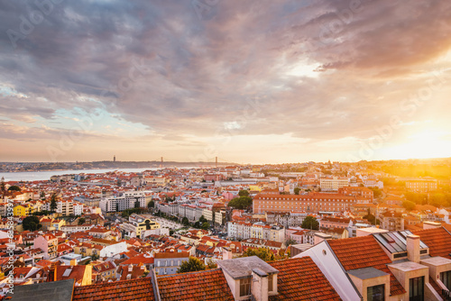 View of Lisbon famous view from Miradouro da Senhora do Monte tourist viewpoint of Alfama and Mauraria old city district, 25th of April Bridge at sunset. Lisbon, Portugal