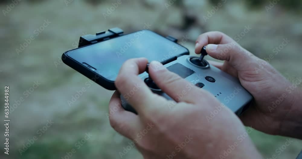Close-up of hands controlling a drone using the remote control in the evening