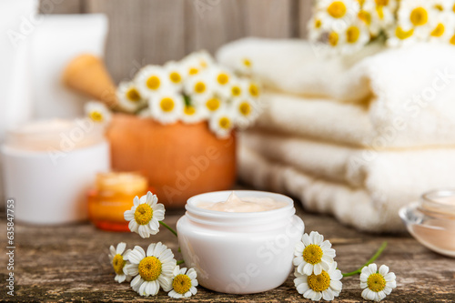 Open jar of cream for face  body and hands with chamomile flower on a wooden background. Herbal dermatological cosmetic hygiene cream. Natural cosmetic product. Beauty concept. Cosmetic tube.MOCKUP.
