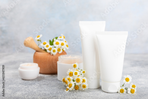 Open jar of cream for face  body and hands with chamomile flower on a blue background. Herbal dermatological cosmetic hygiene cream. Natural cosmetic product. Beauty concept. Cosmetic tube.MOCKUP