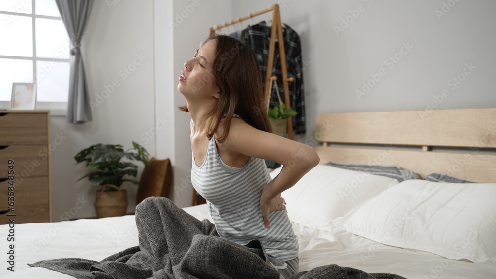 Sad young asian woman touching back feeling backache in morning. tired